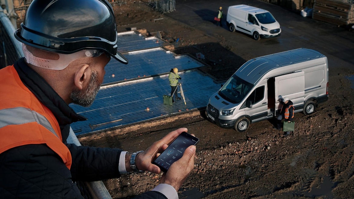 Man in high vis jacket at a building site using the FordPass Pro app on his phone