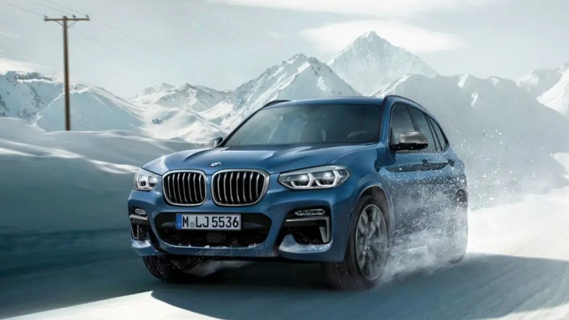 BMW X5 driving past mountains in the snow
