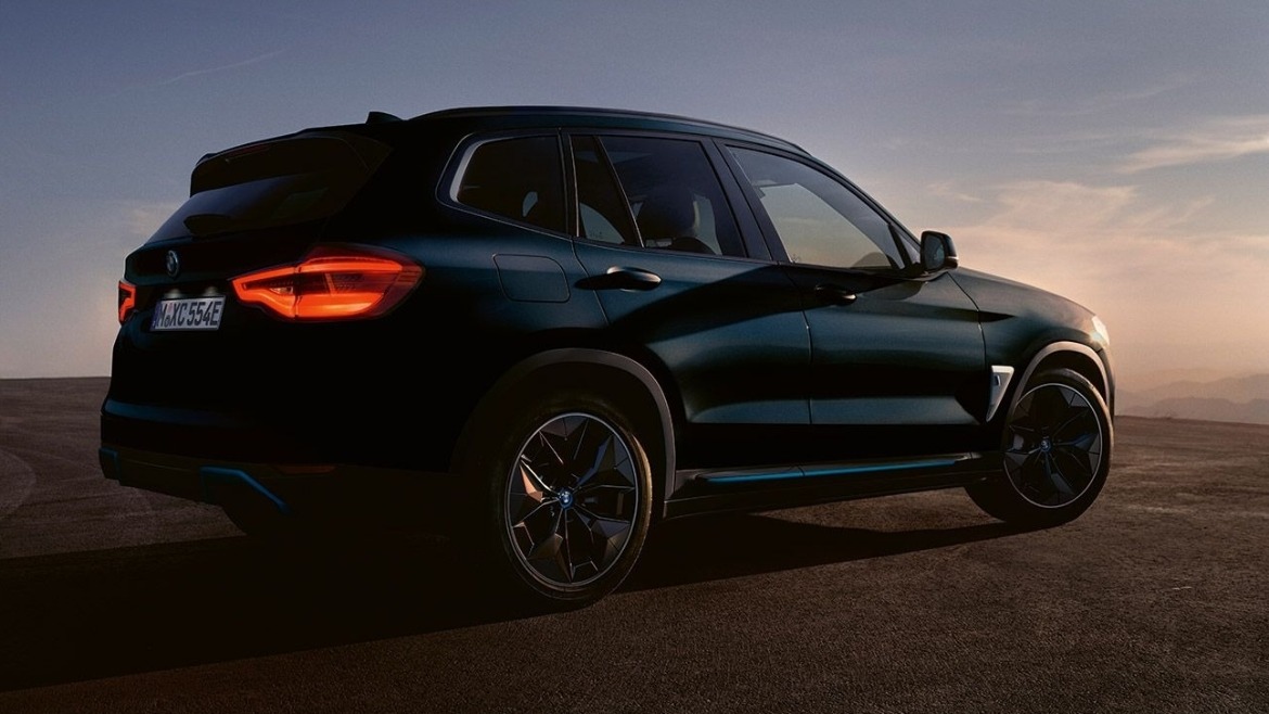 BMW iX3 parked with a sunset in front of it