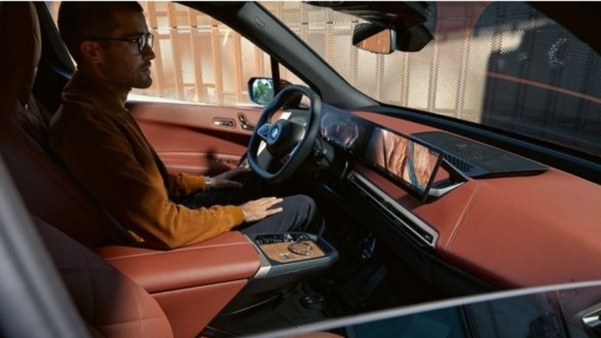Inside the BMW iX with a man sat in the driver's seat
